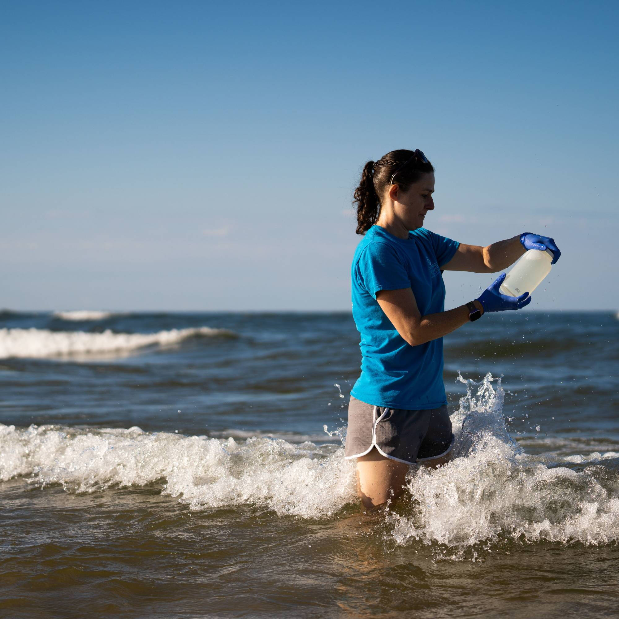 Photograph of a GVSU student standing in knee-deep water taking samples.